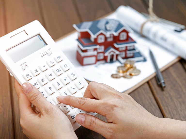 A female hand operating a calculator in front of a Villa house model